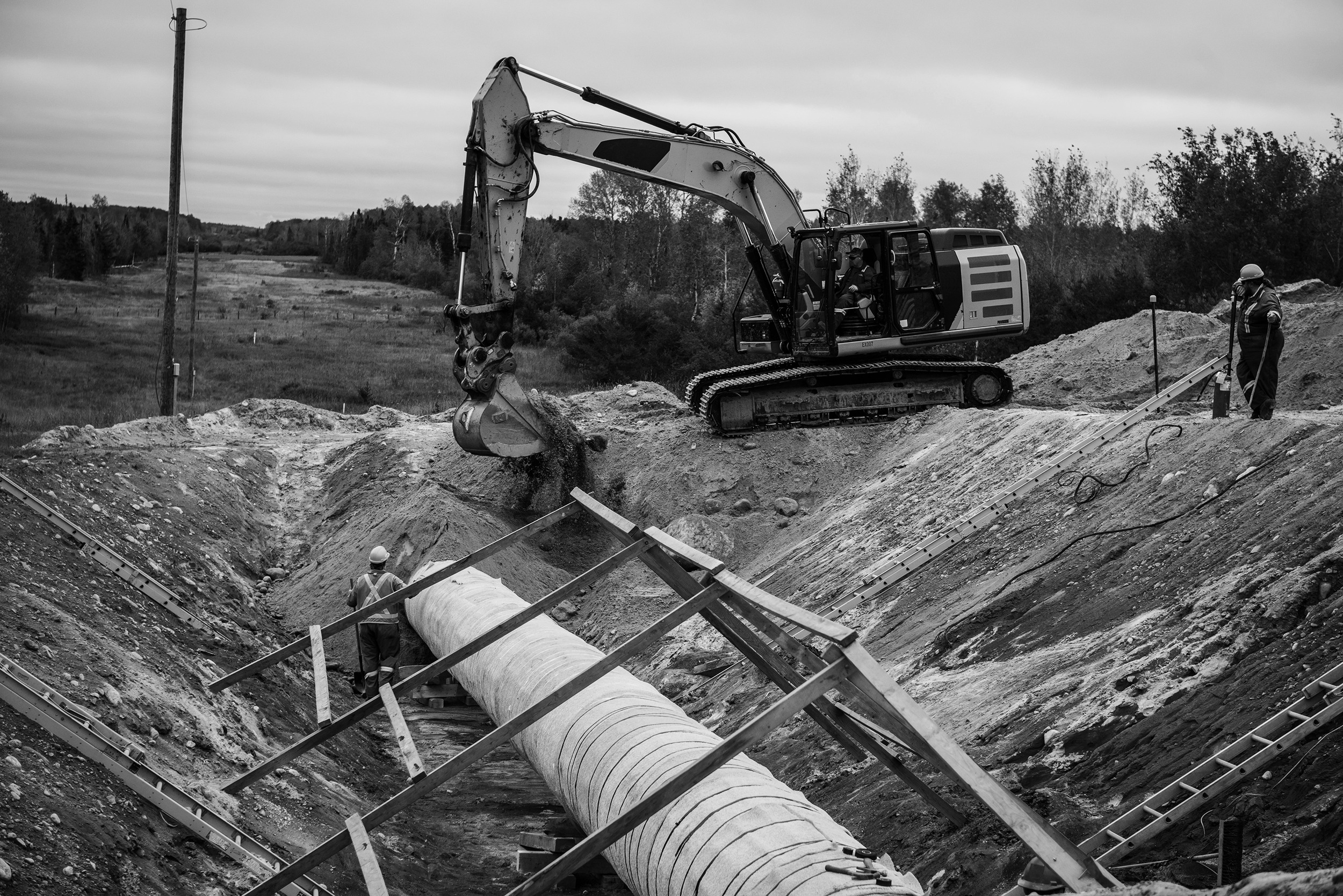 An excavator backfilling a pipeline dig site.